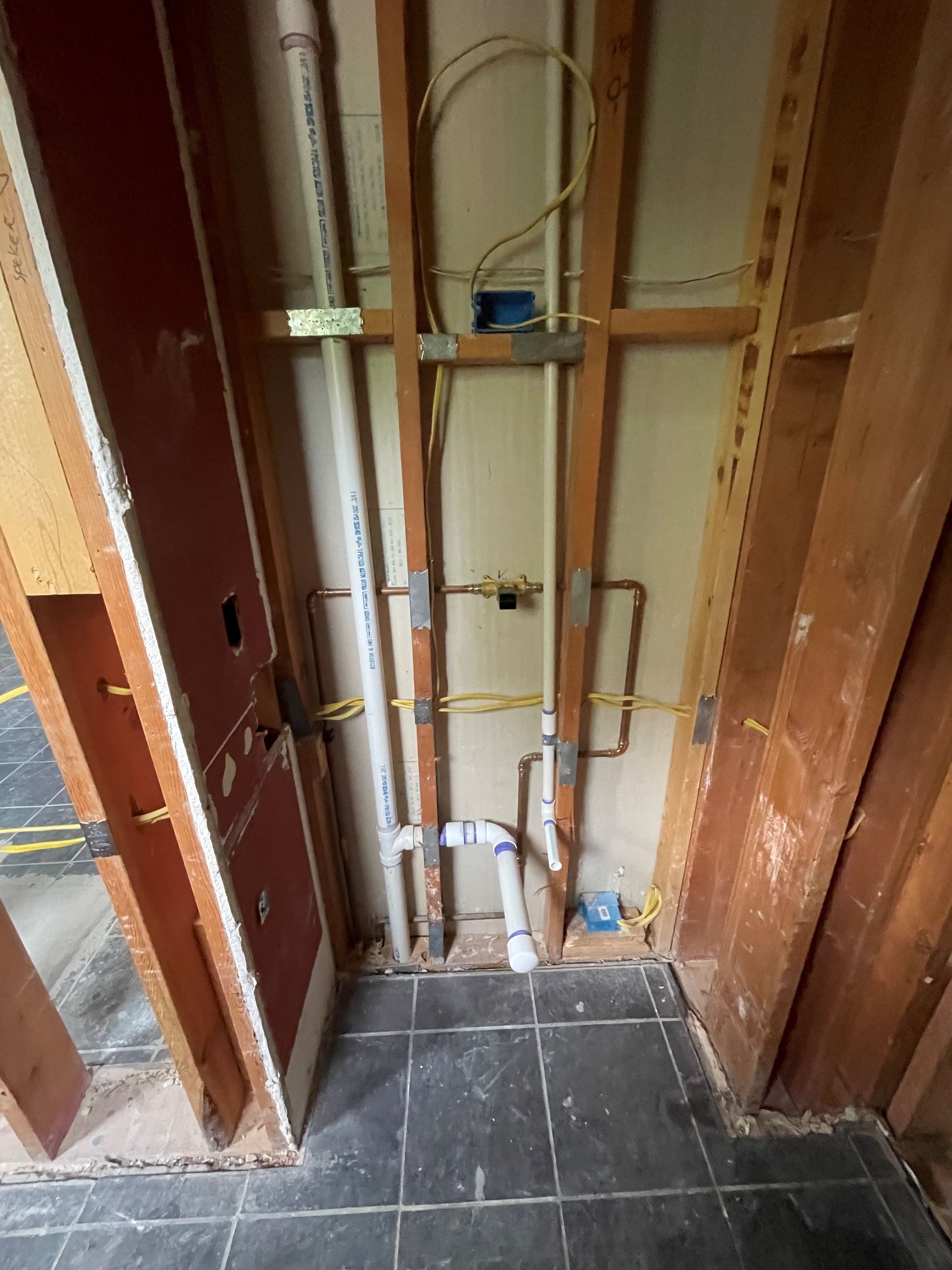 A bathroom under construction with pipes hanging from the ceiling.
