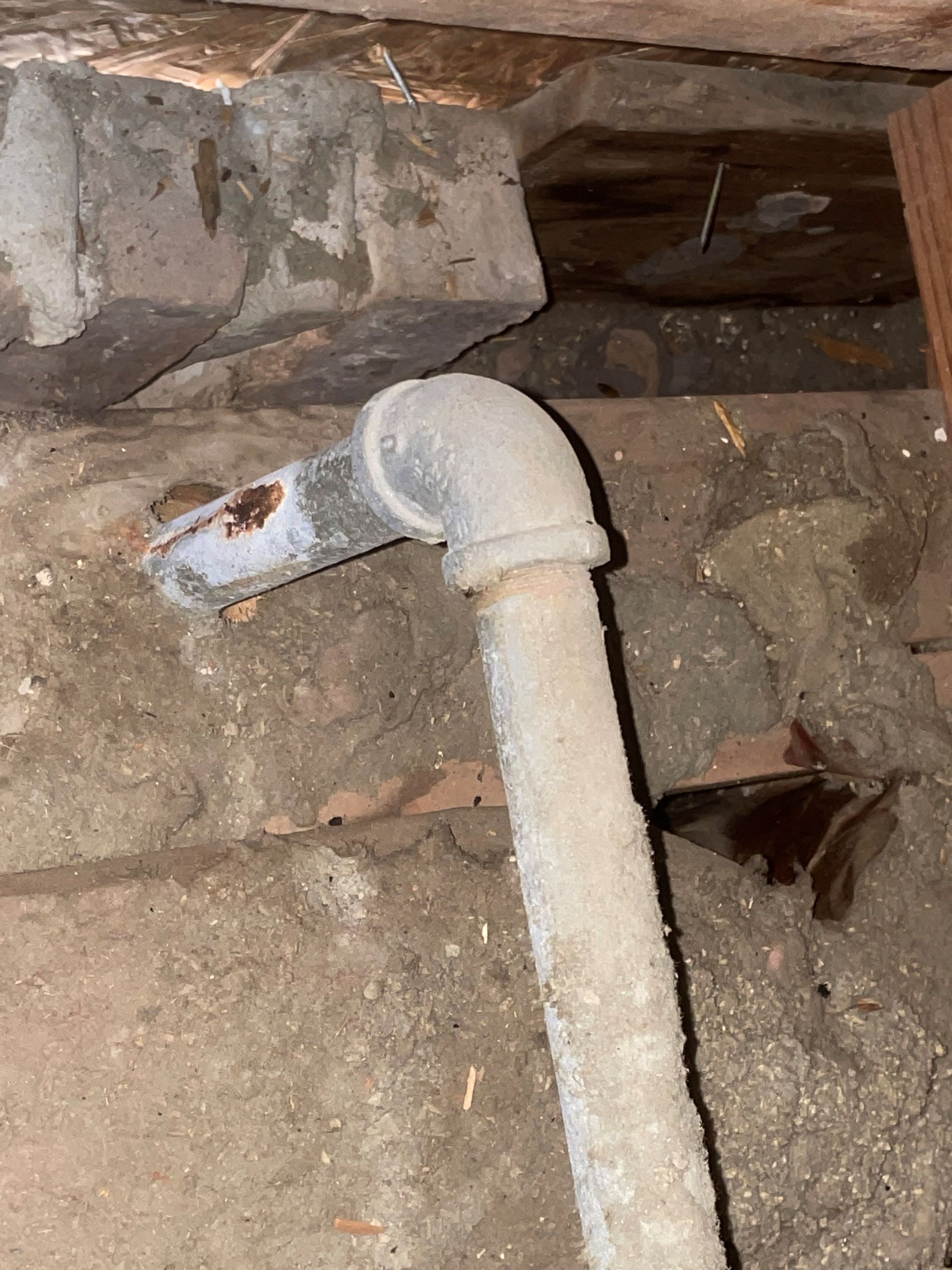 A close up of a rusty pipe in a basement.