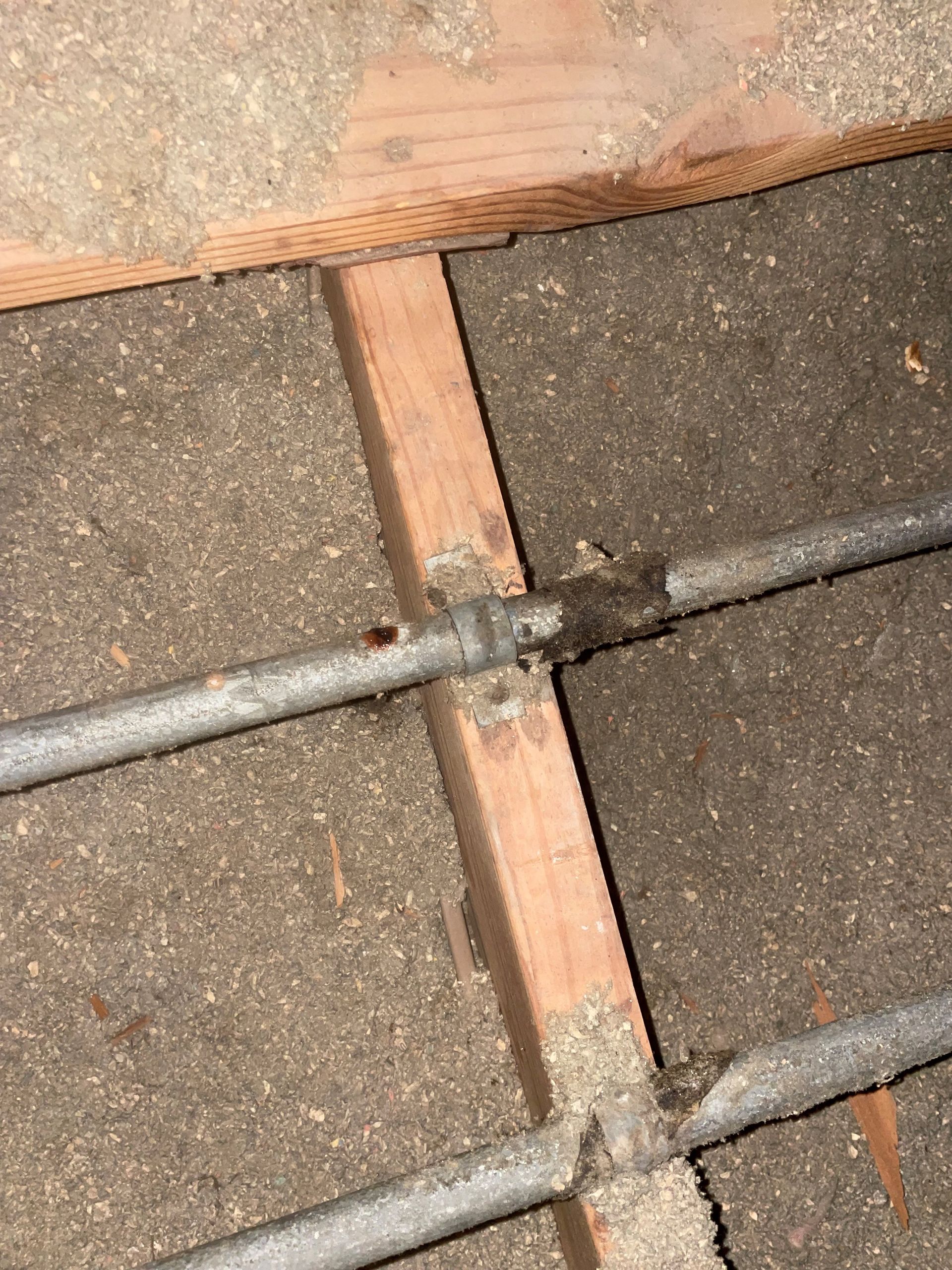 A close up of a metal pipe between two wooden boards.