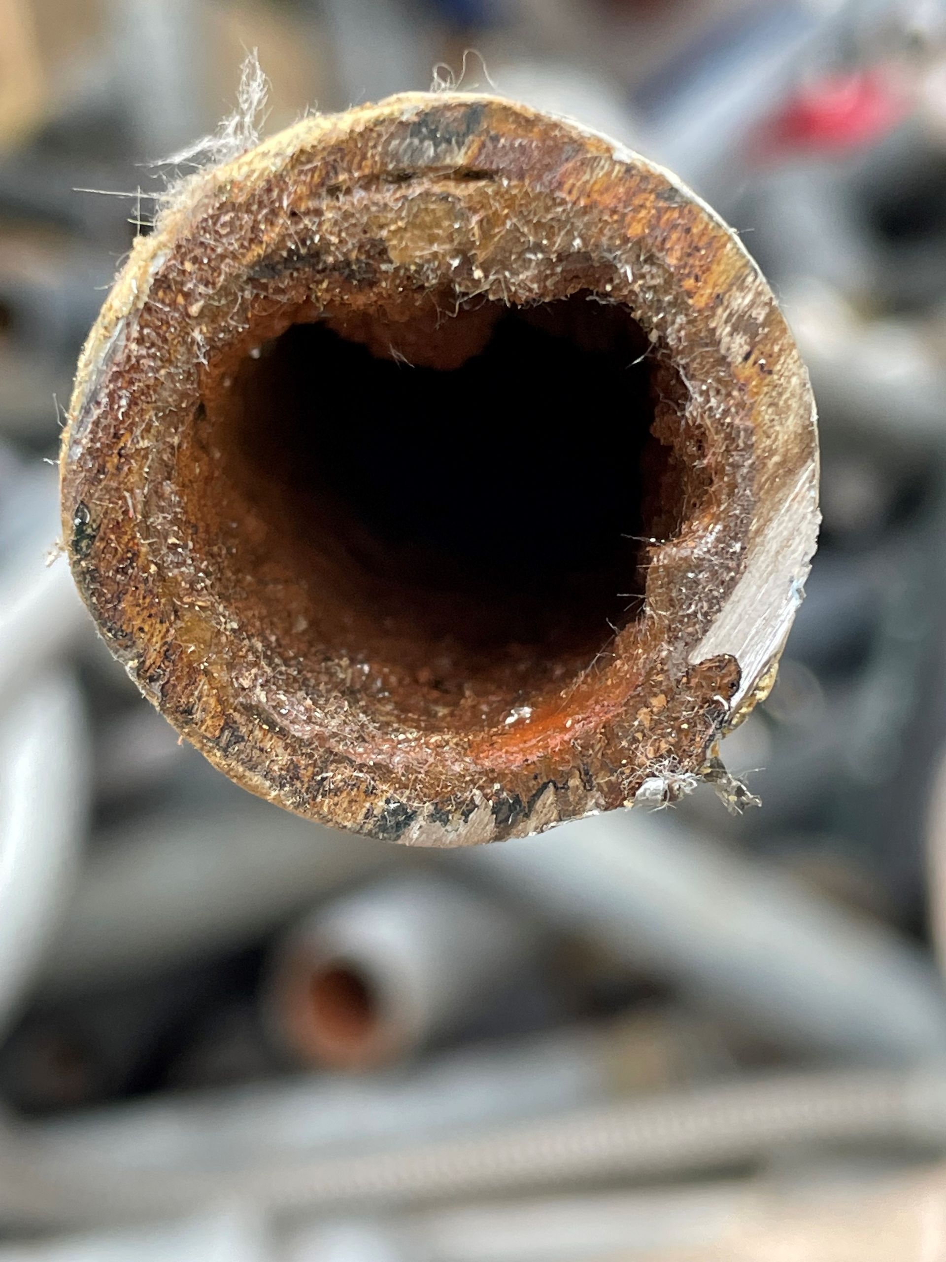 A close up of a rusty pipe with a hole in the middle.