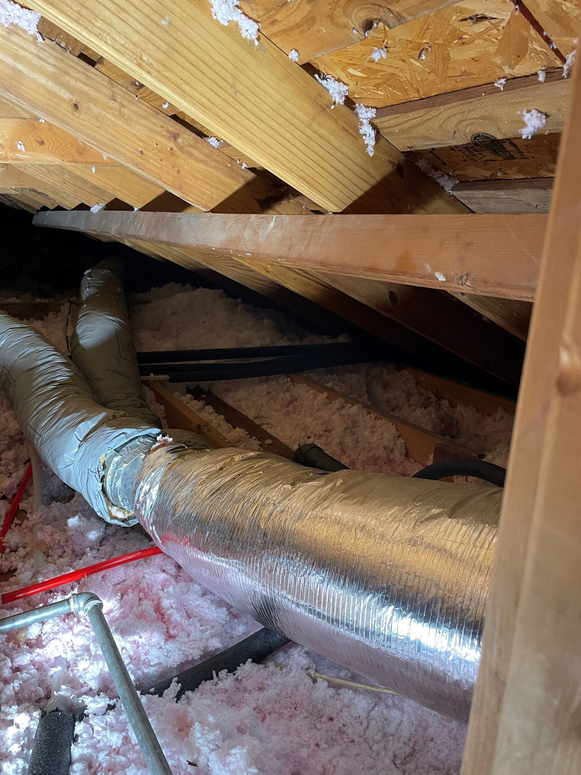 There is a pipe in the attic of a house.