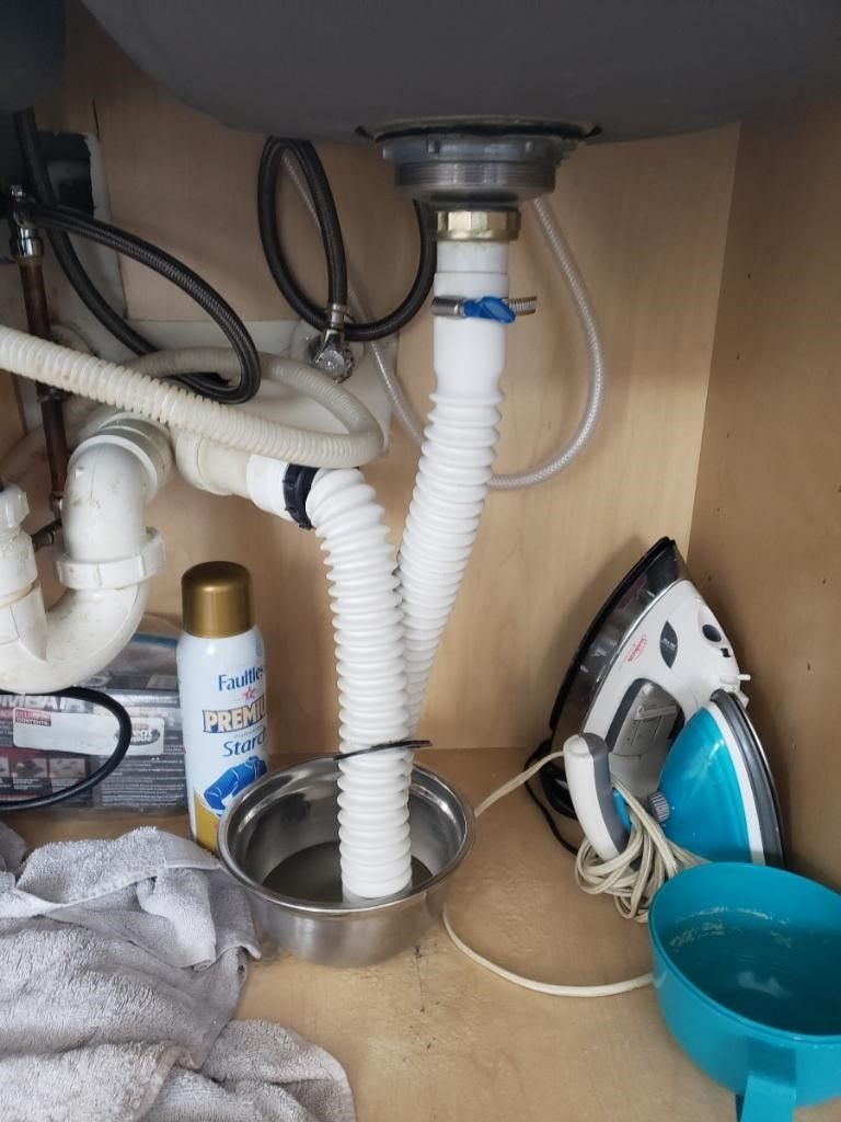 A sink underneath a cabinet with a hose coming out of it.