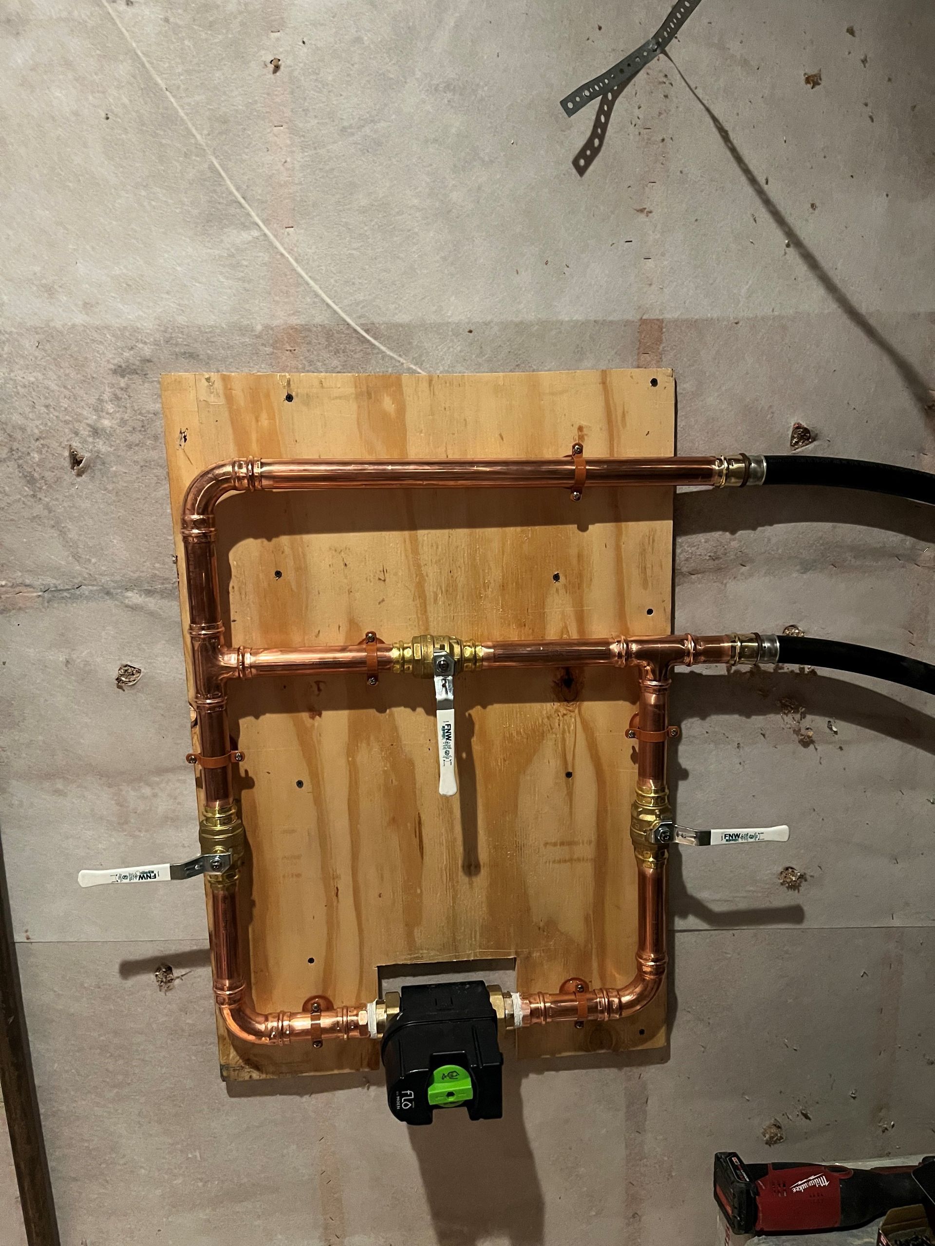 Copper pipes are being installed on a wooden board