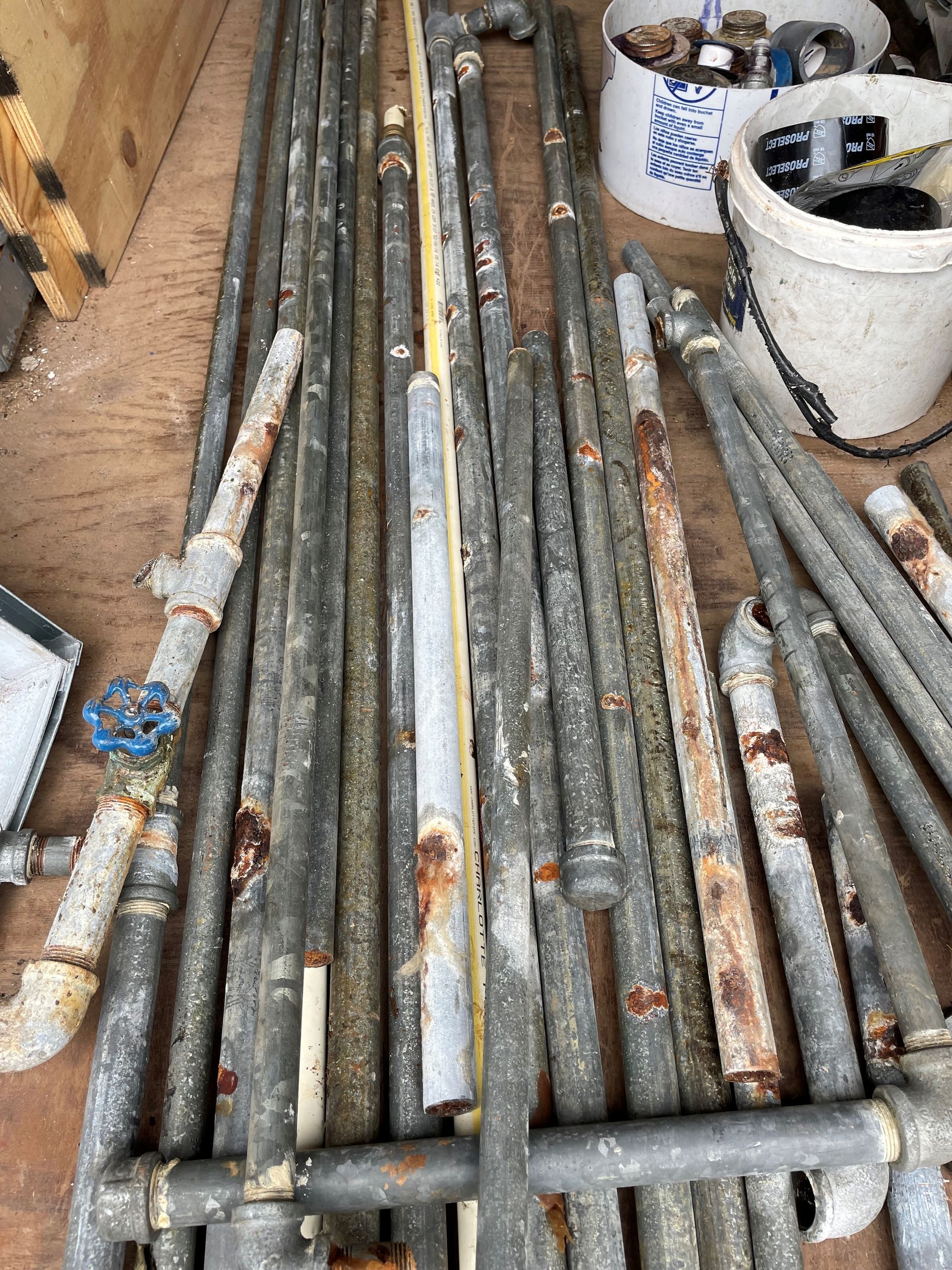 A bunch of metal pipes are stacked on top of each other on a wooden floor.