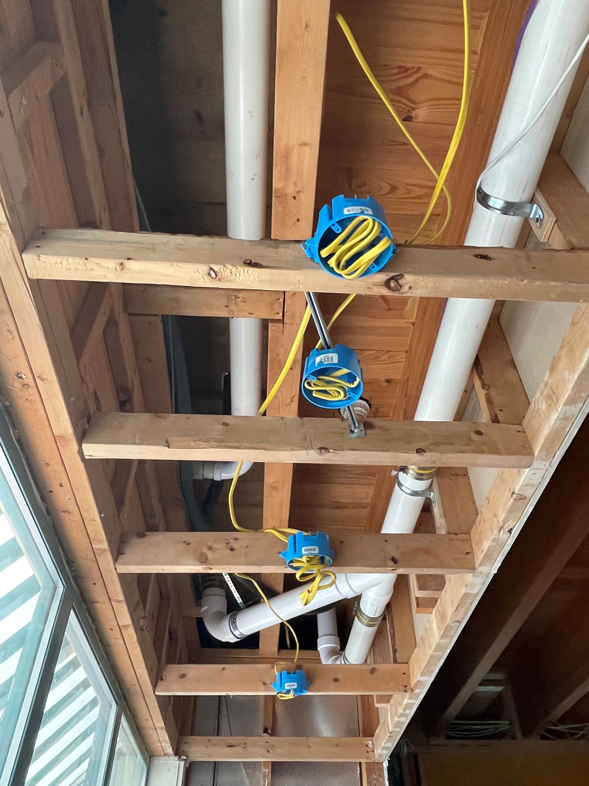 A ceiling with pipes and wires hanging from it.