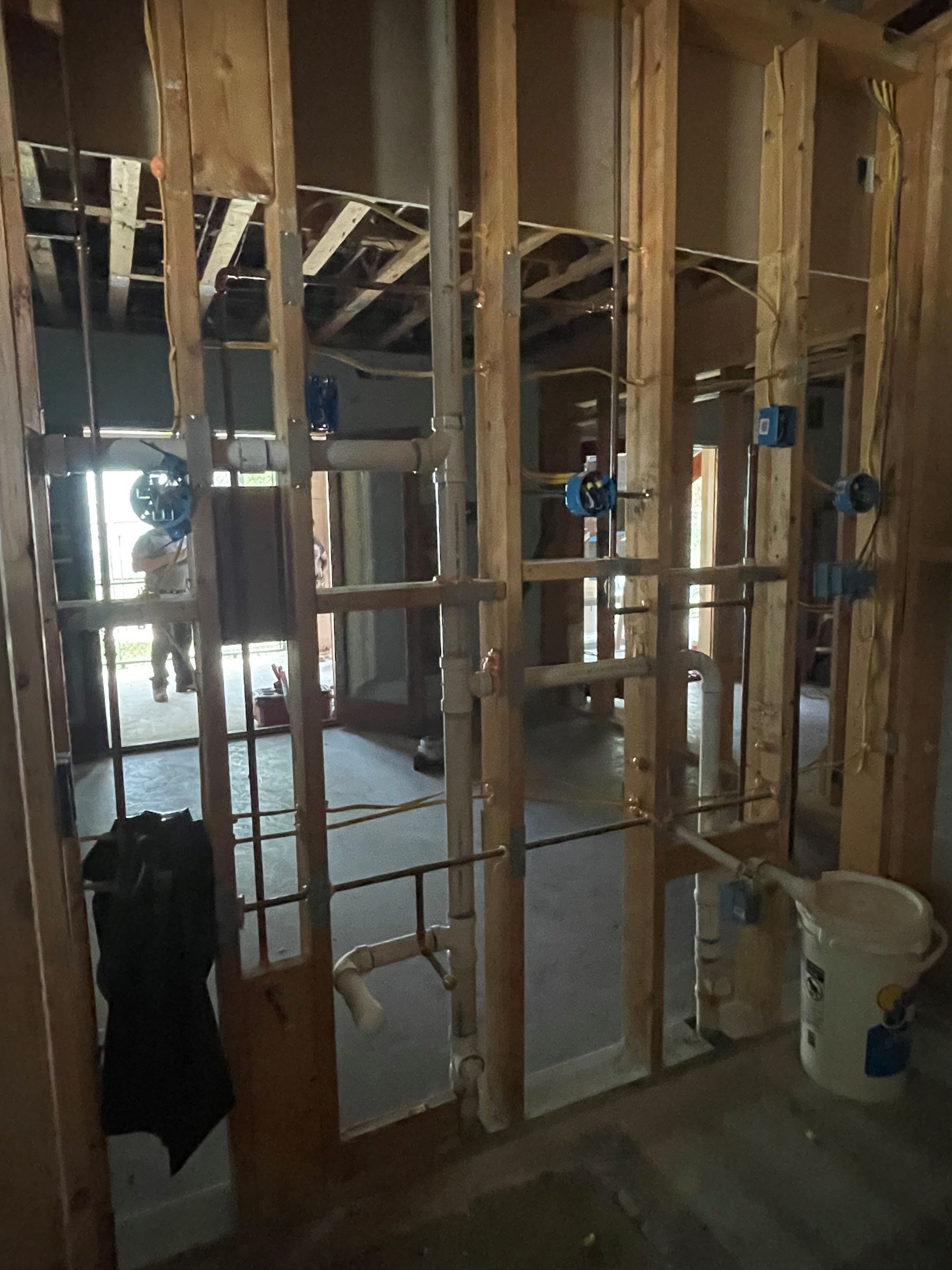 A bucket of paint sits in the middle of a room under construction