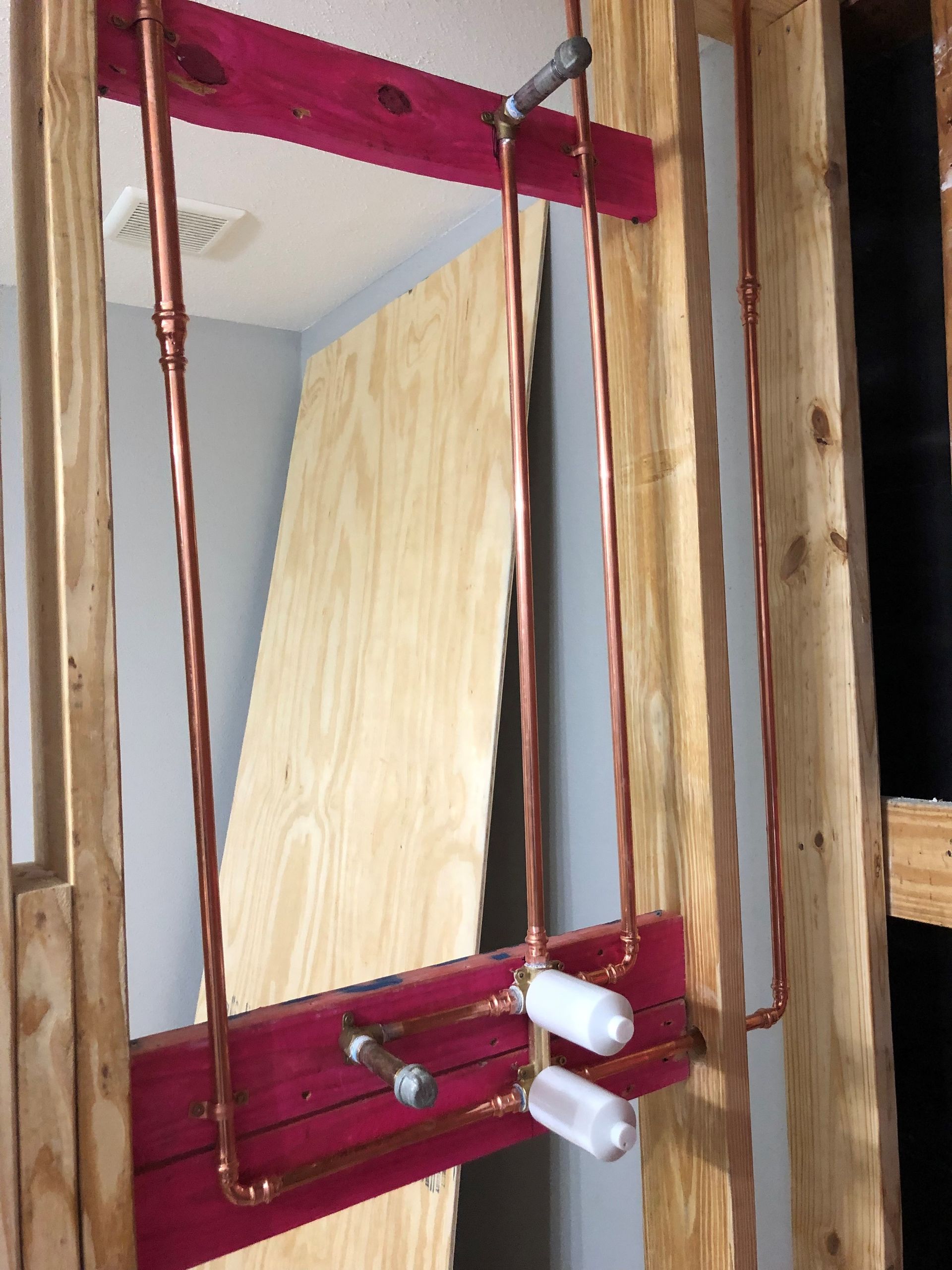 A bathroom mirror with copper pipes hanging from it