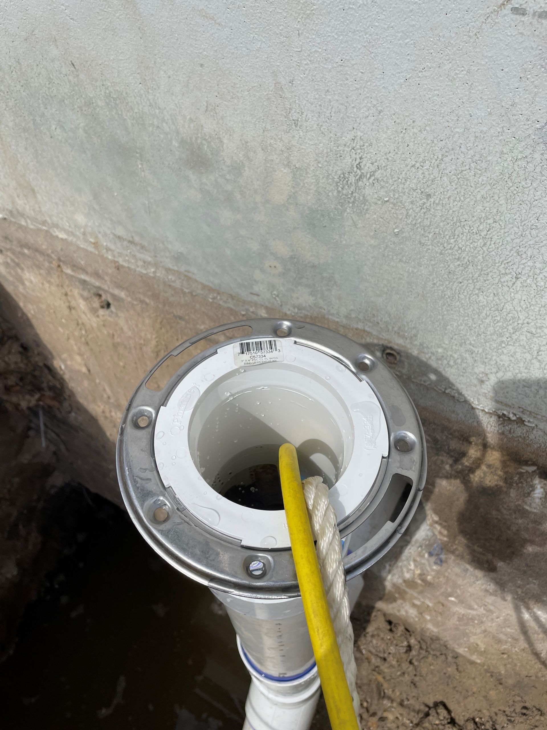 A close up of a drain with a yellow hose attached to it.