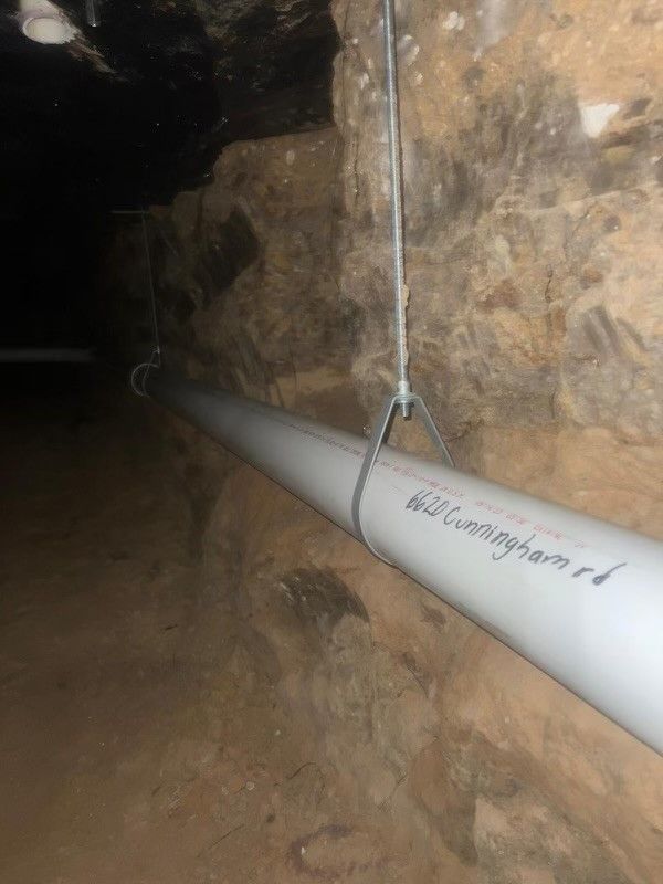 A white pipe is hanging from the ceiling of a cave.