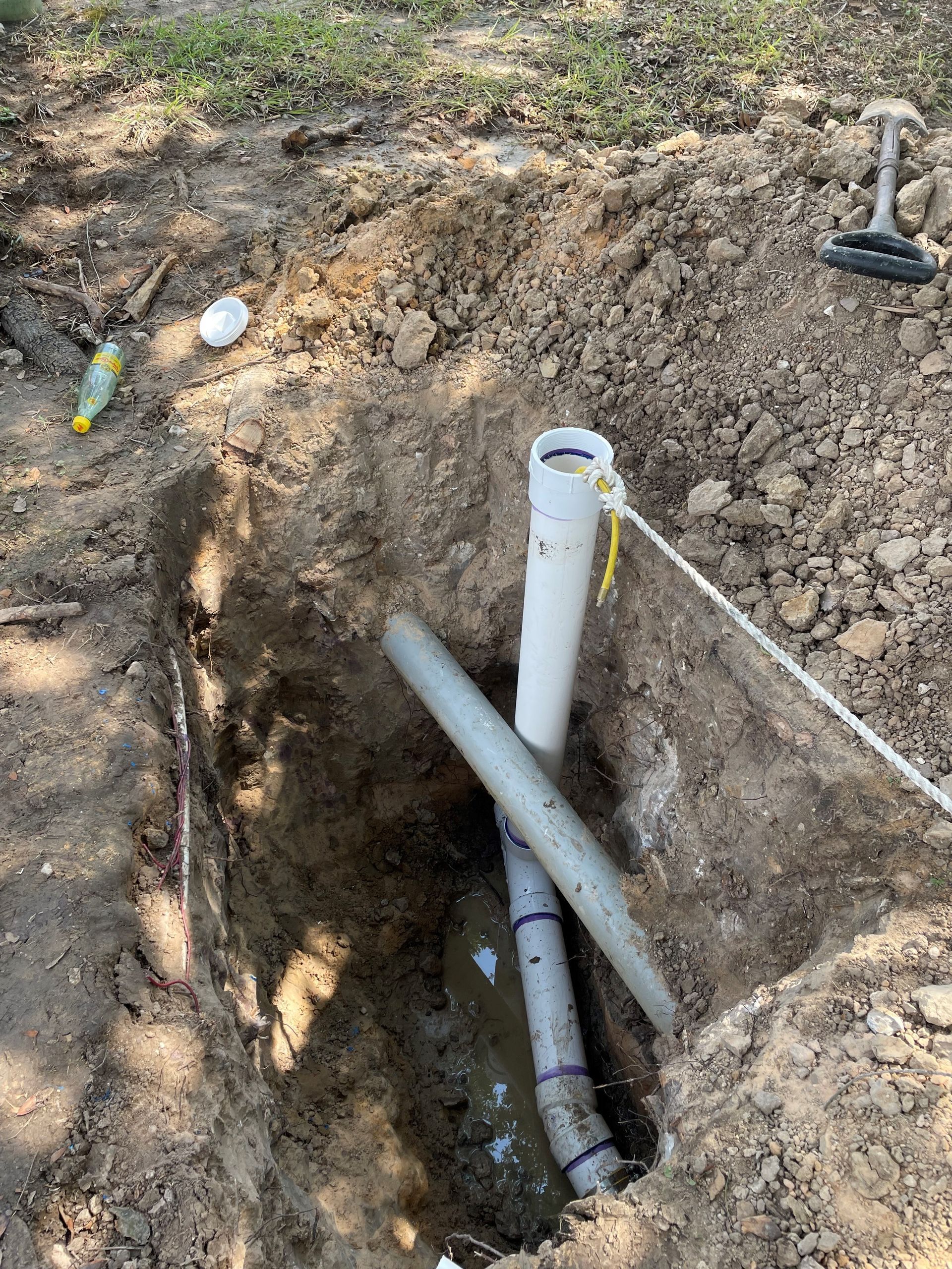 A pipe is laying in the dirt in a hole.