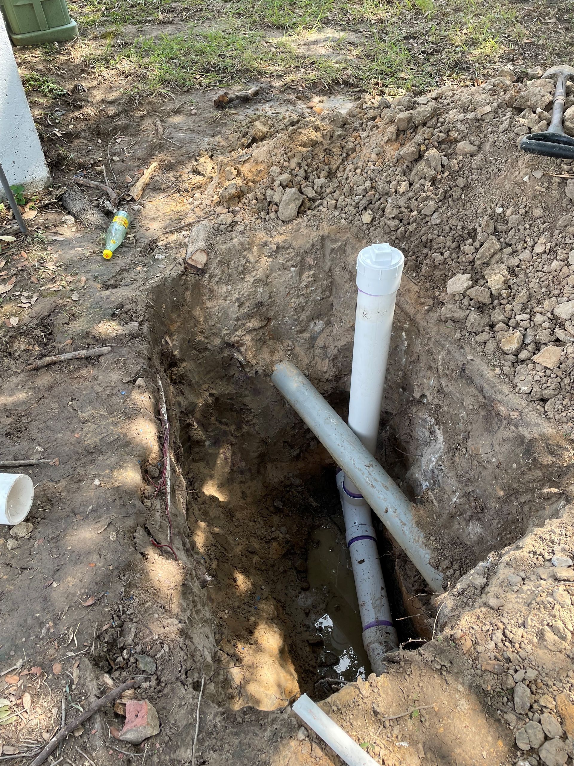 A pipe is laying in the dirt in a hole.