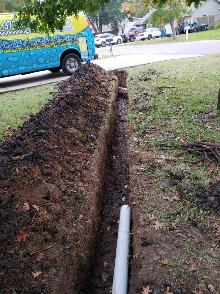 A pipe is being installed in a trench next to a truck.