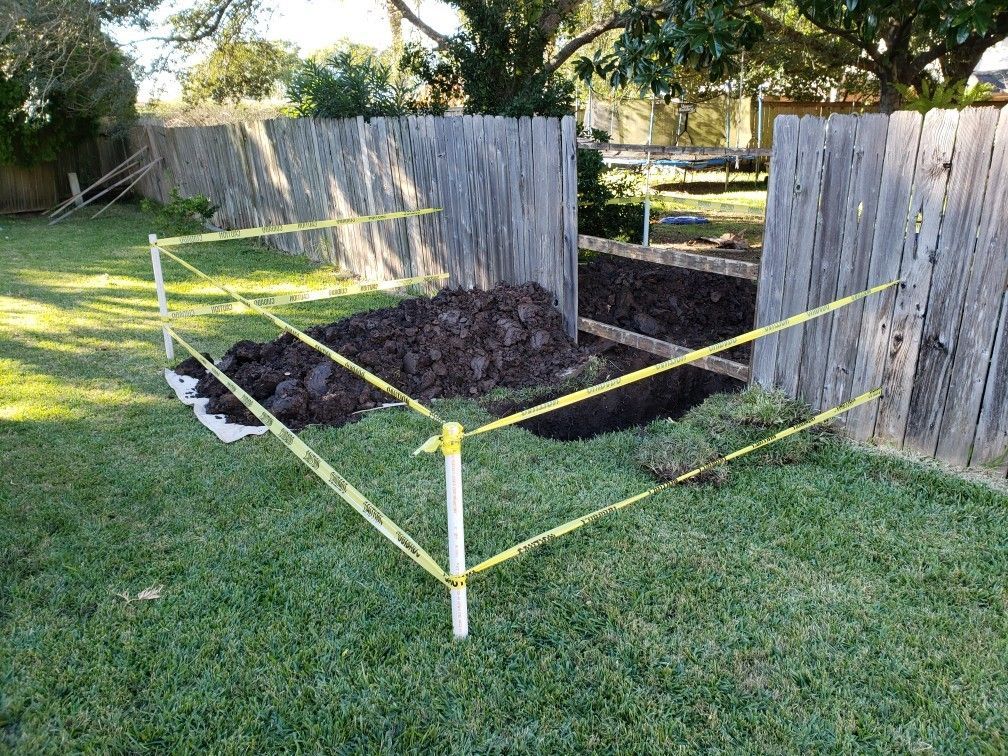 A large pile of dirt is sitting in the grass next to a wooden fence.