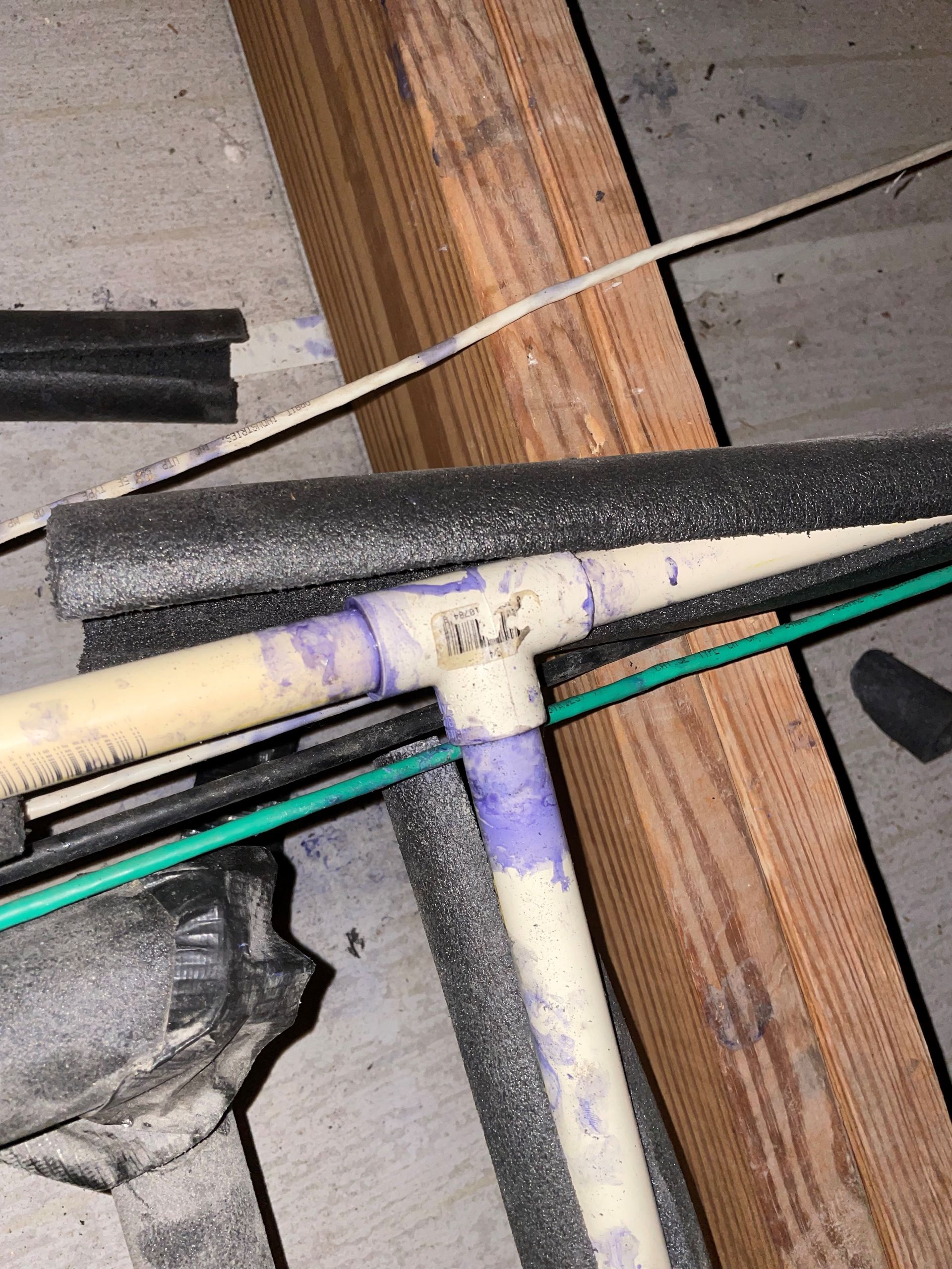 A close up of a pipe with a green wire coming out of it.