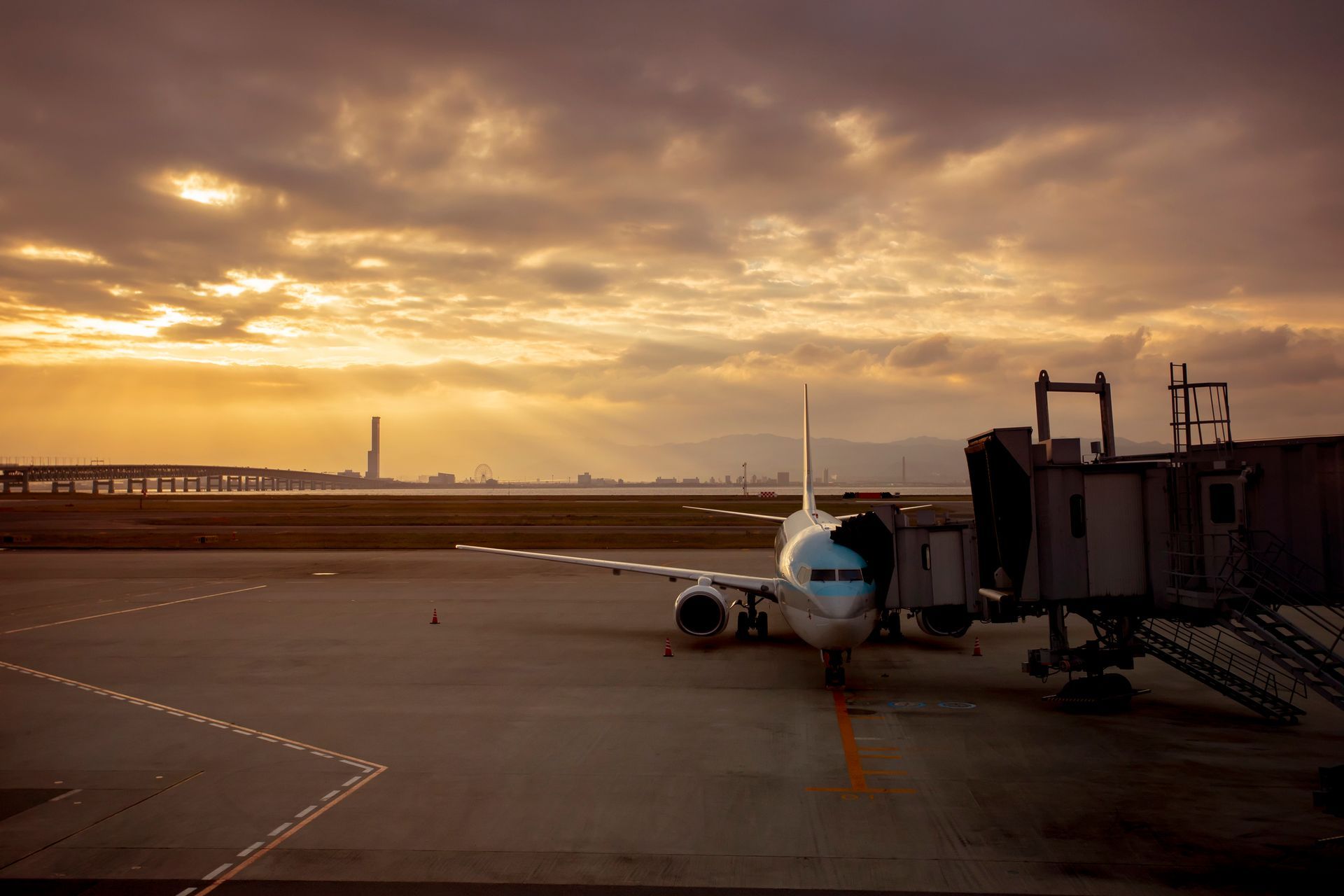 Un aereo è parcheggiato sulla pista di un aeroporto al tramonto.