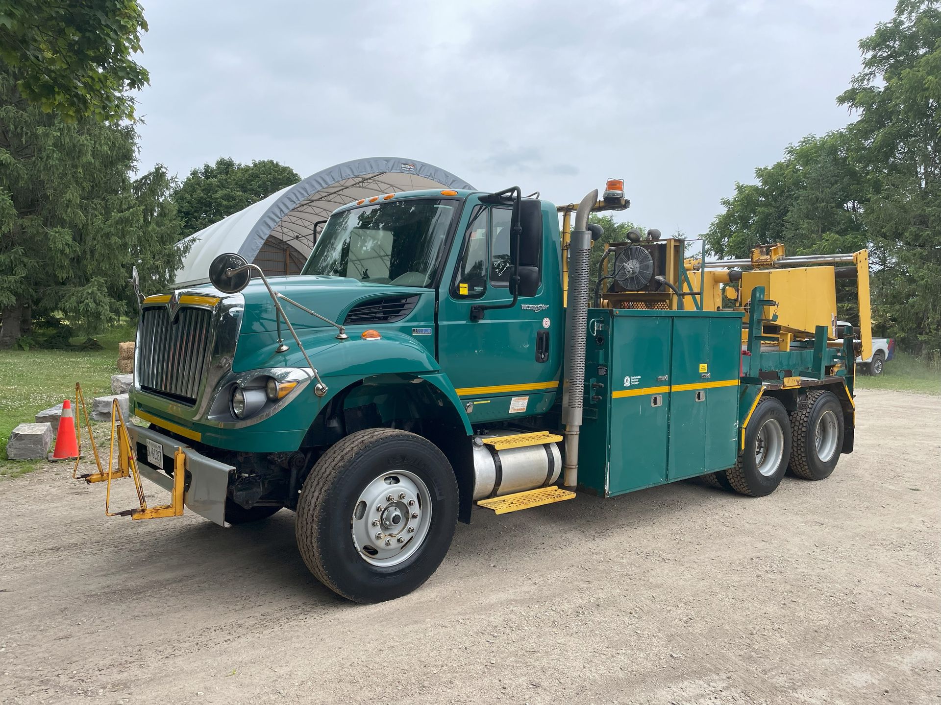 A green and yellow truck is parked in a gravel lot.