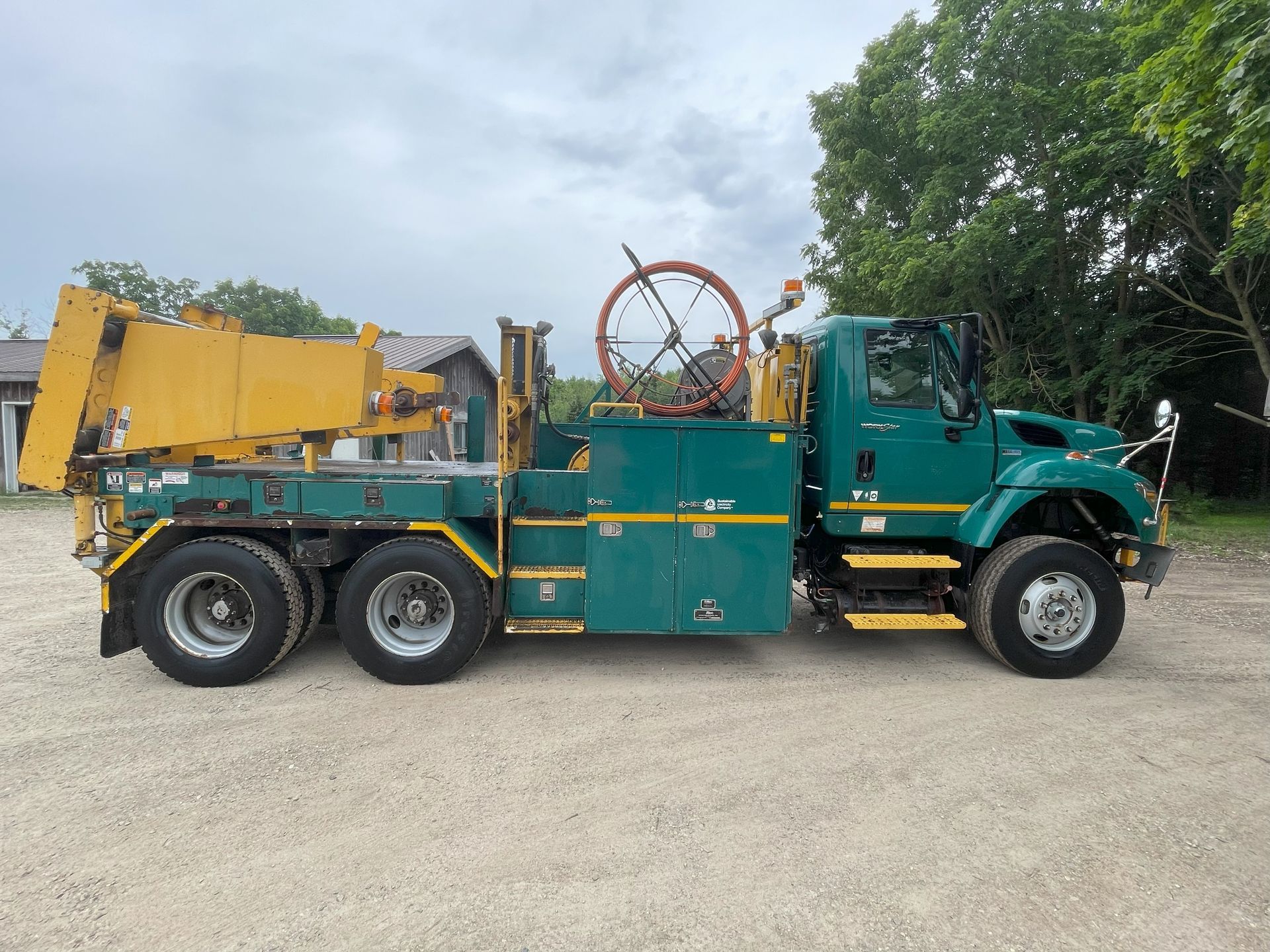 A green and yellow truck is parked in a gravel lot.