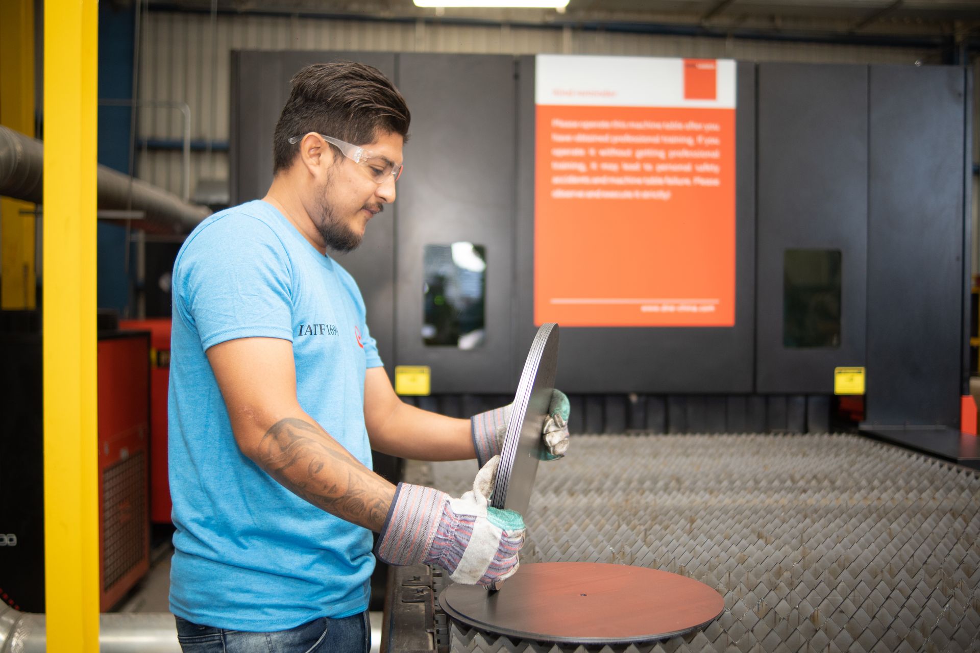 un hombre con camisa azul está trabajando en una máquina en una fábrica.
