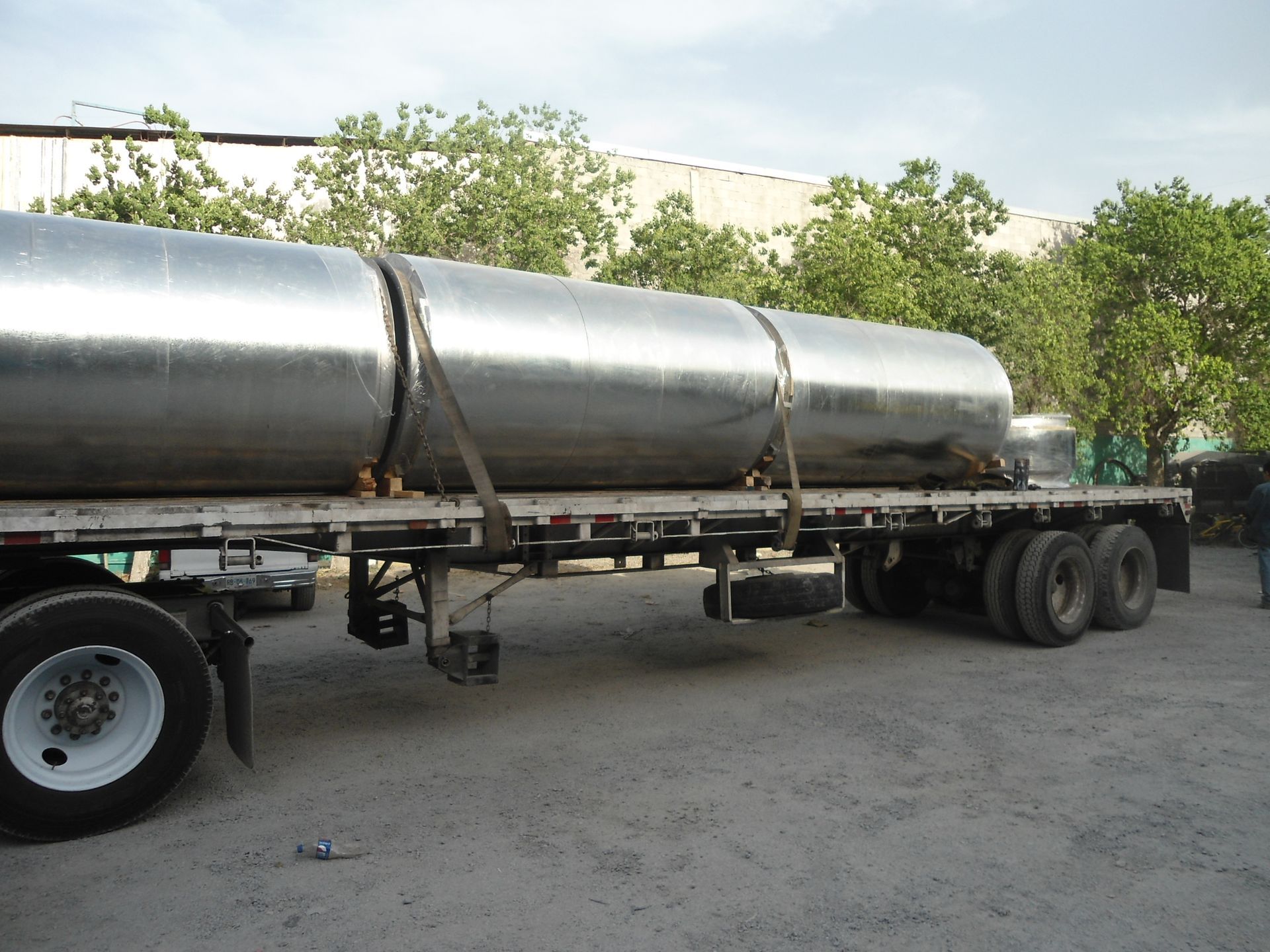un camión que transporta grandes tubos metálicos está estacionado en un estacionamiento