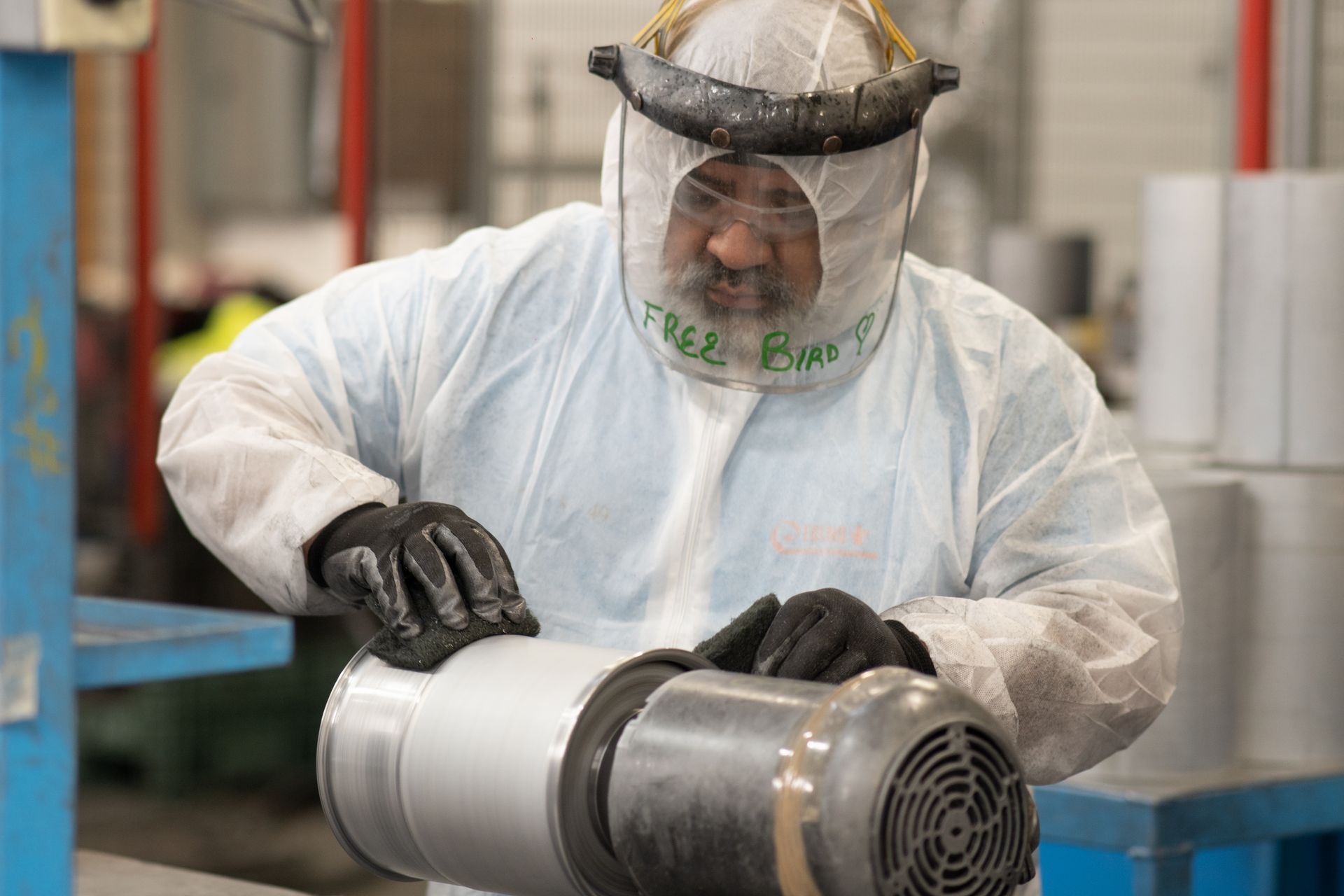 Un hombre con traje protector está trabajando en una máquina en una fábrica.