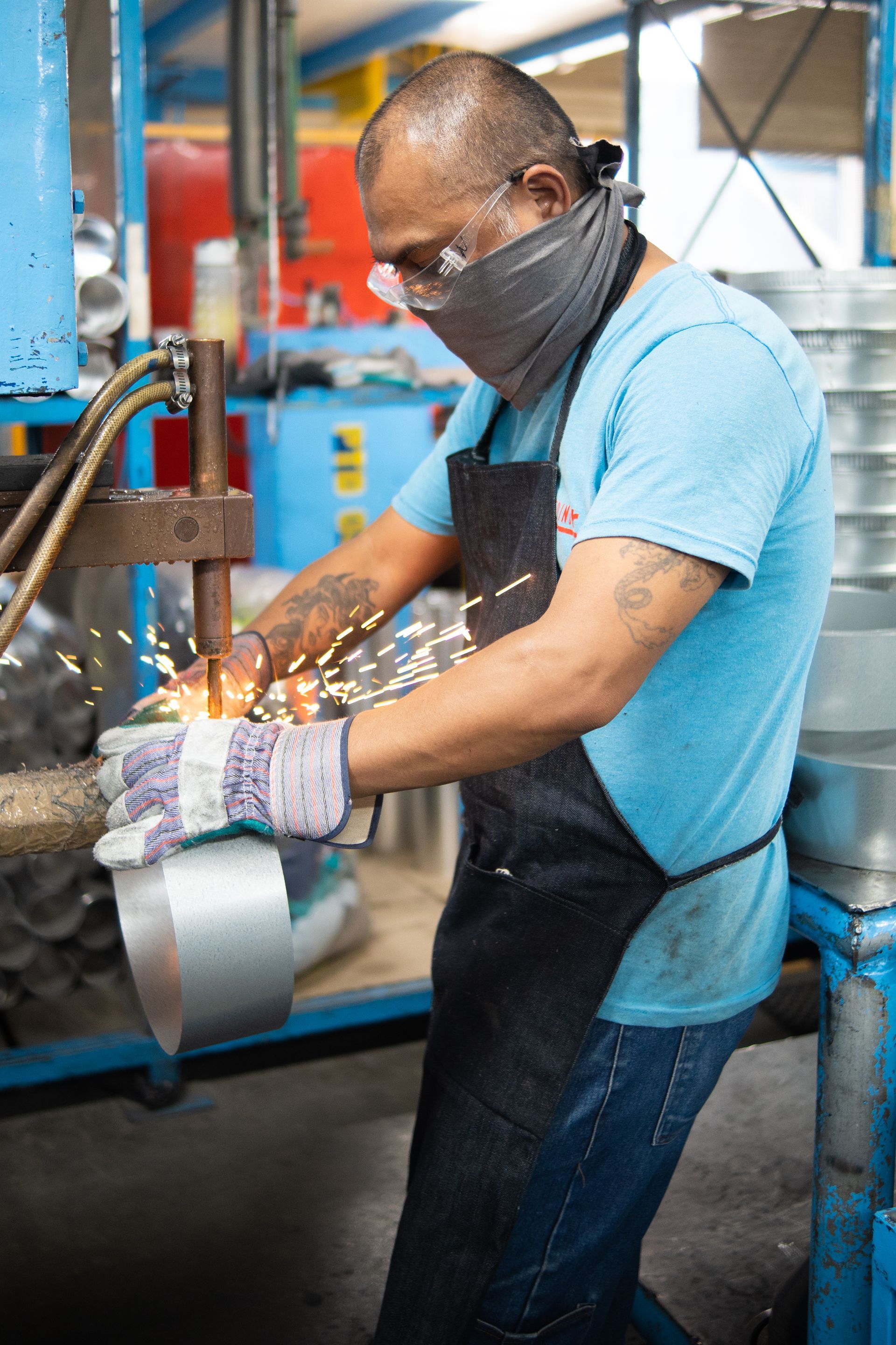 Un hombre con máscara y guantes trabaja en una máquina en una fábrica.