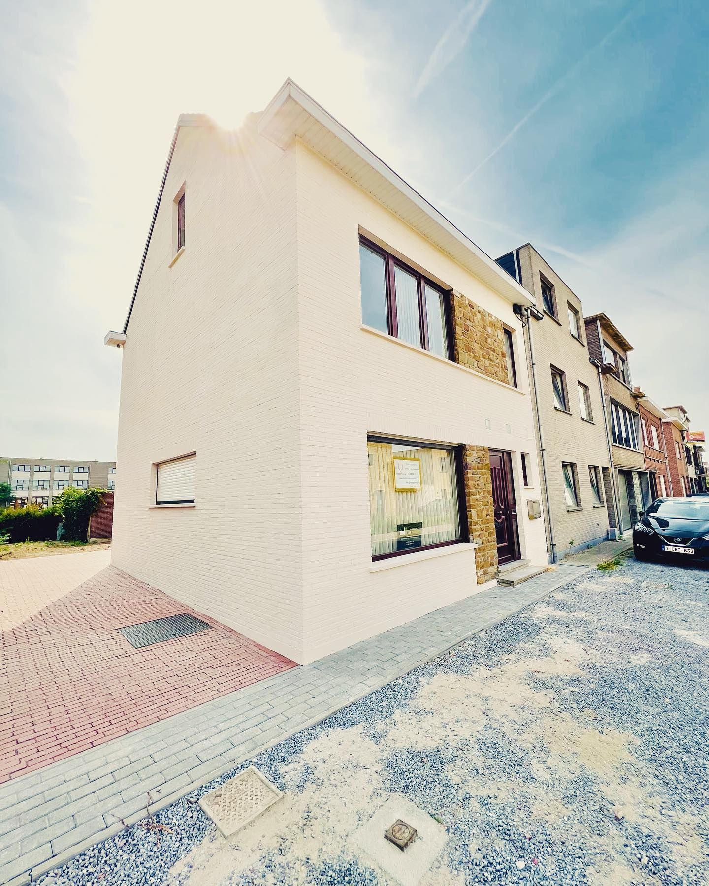 Een wit gebouw met veel ramen en een auto ervoor geparkeerd