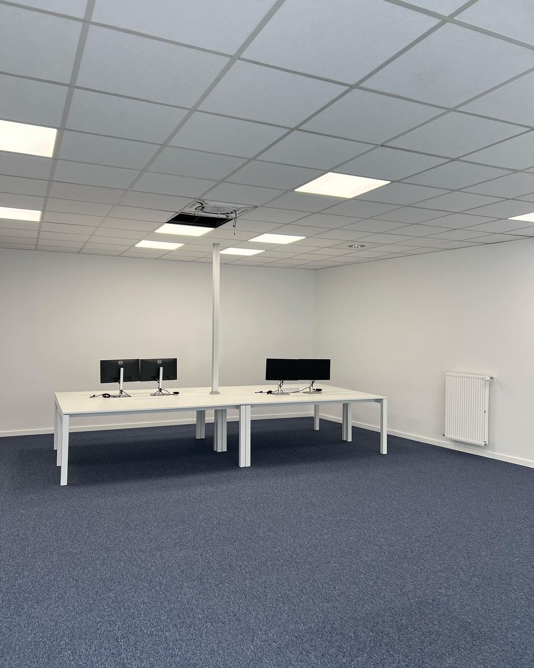 Een leeg kantoor met twee bureaus en twee monitoren