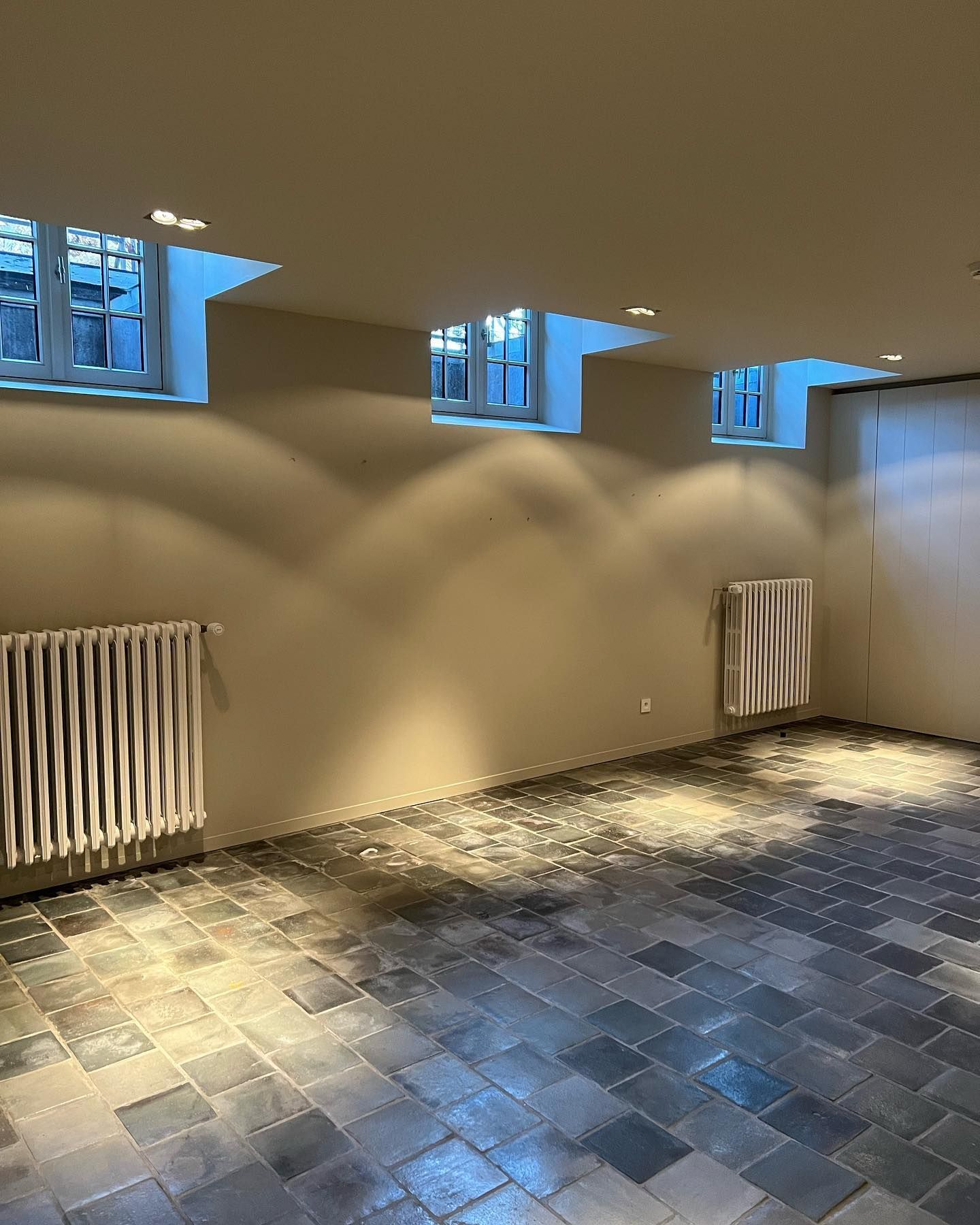 Een lege kamer met een betegelde vloer en een radiator.