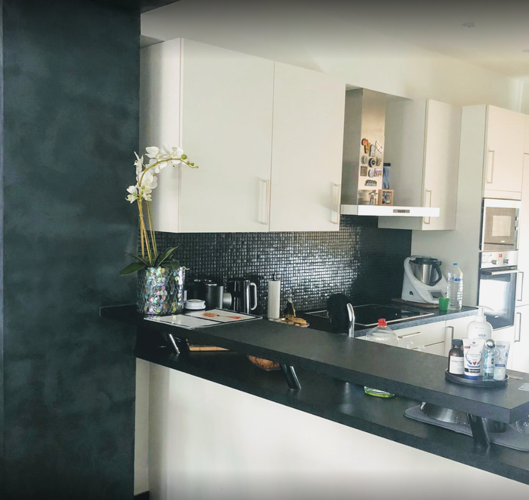 Een keuken met witte kasten en een zwart aanrechtblad