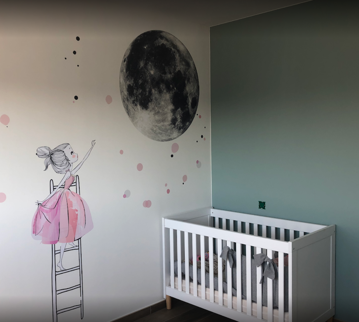 Een babykamer met een wiegje en een schilderij van een meisje aan de muur.
