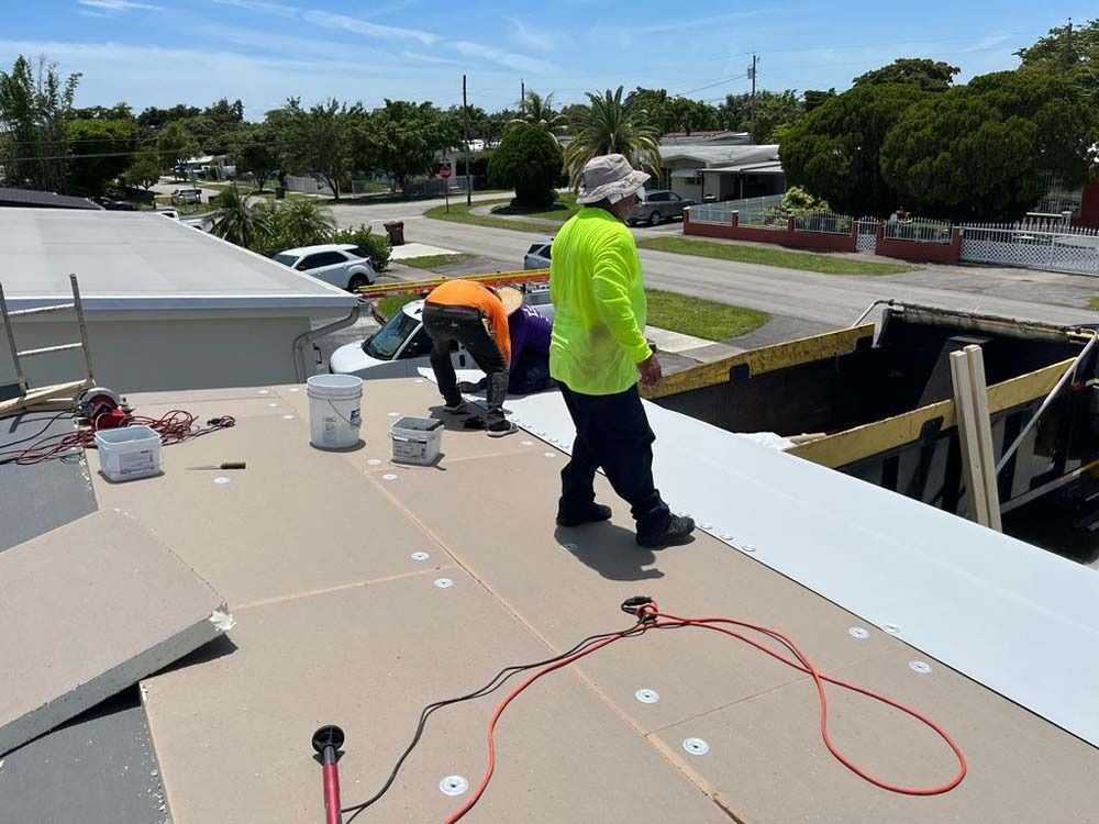 Construction workers install roofing panels on a residential flat roof on a sunny day.