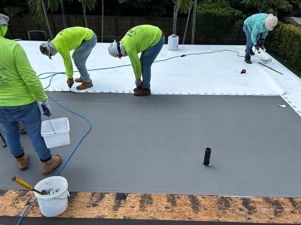 Construction workers in neon yellow shirts install a white membrane roof on a residential building.