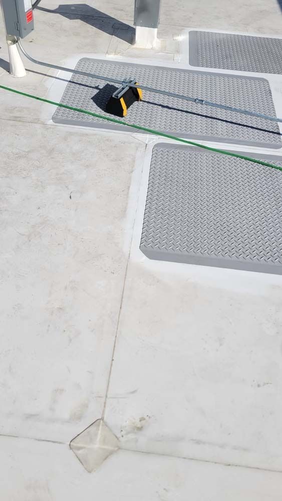 A yellow and black utility cable protector on a flat concrete surface with a thin green wire running across it.