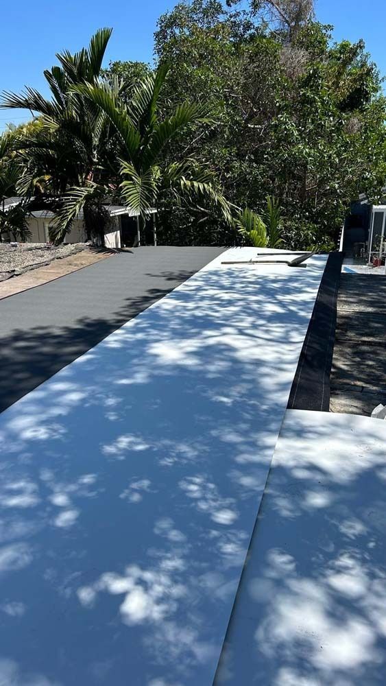 A roof under construction featuring bright white insulating panels contrasted with a dark gray surface, set outdoors.