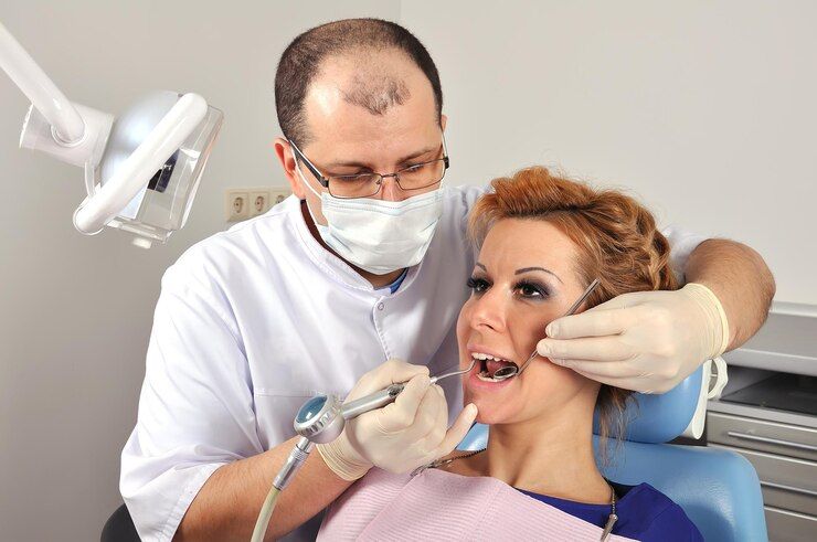 A dentist is examining a woman's teeth in a dental chair.