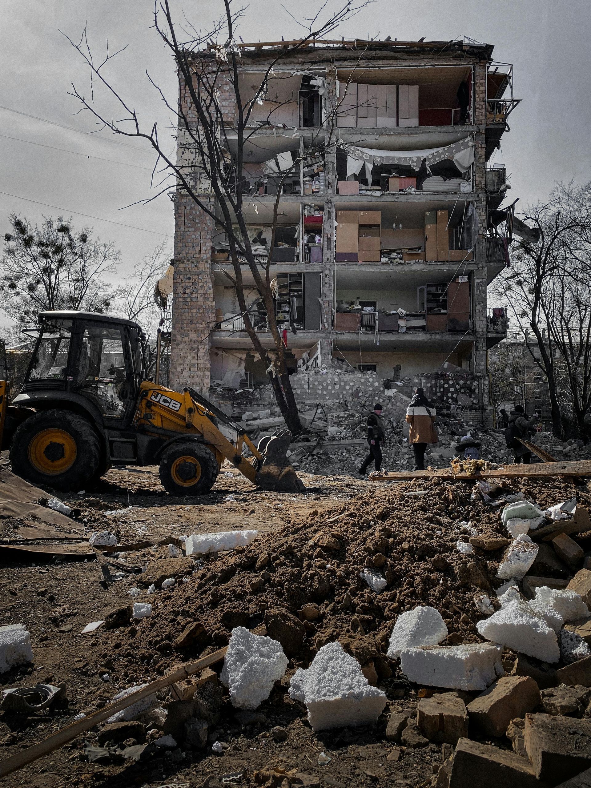 A tractor is working on a building that is being demolished.