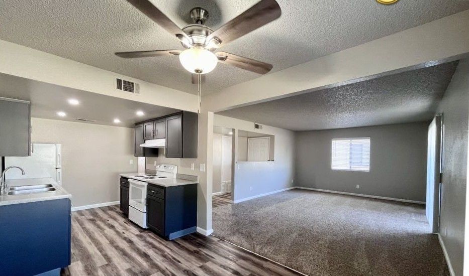 Interior of a modern apartment with a kitchen, living room, and ceiling fan.