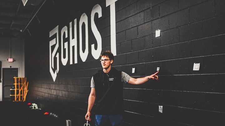 Coach Ryno pointing at vision training cards on Ghost wall