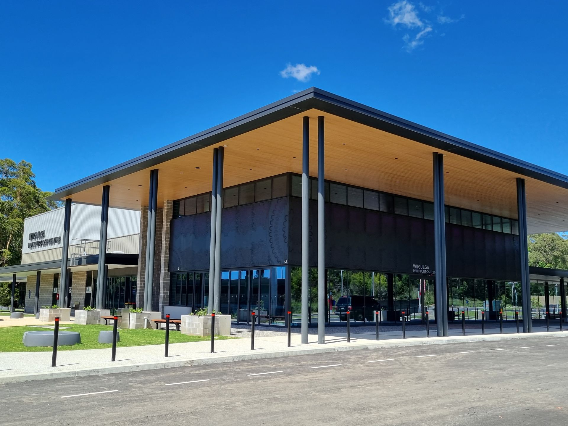Modern, two-story building with a flat roof. Columns support an overhang. Clear blue sky.