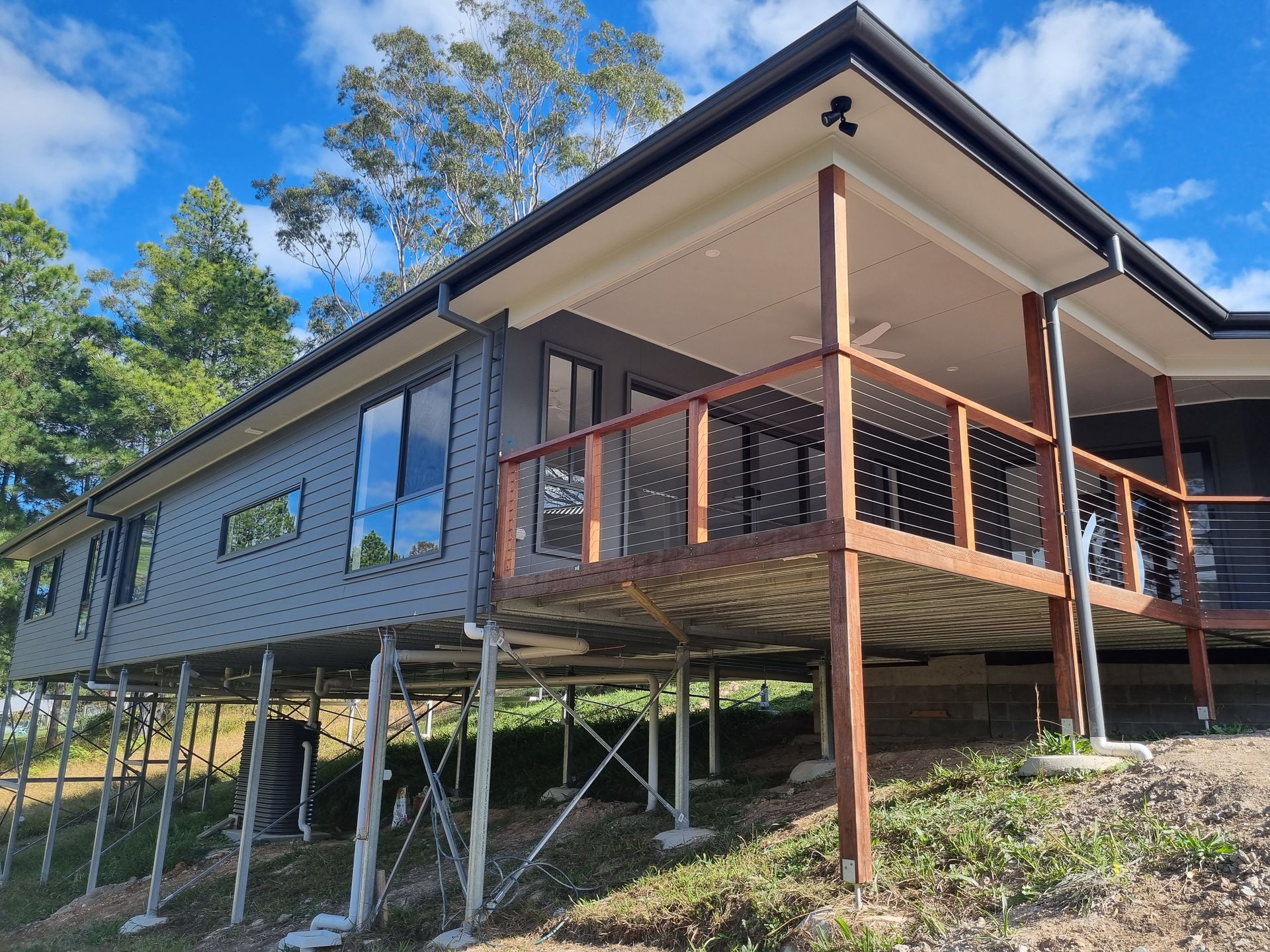 Elevated Grey House With a Deck, Supported by Metal Posts — Acheson Building Certification in Nambucca Heads, NSW