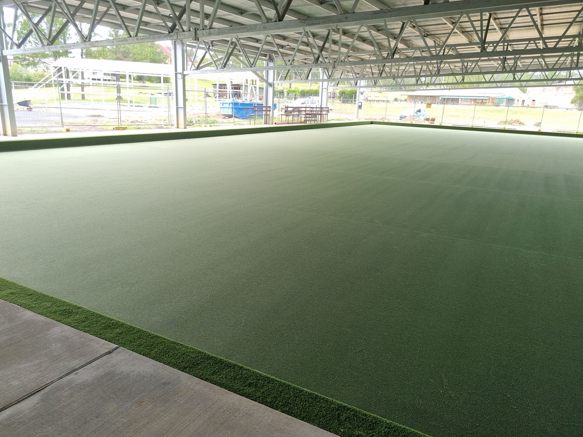 A large, indoor artificial turf field under a metal roof. The field is green, bordered by darker green.