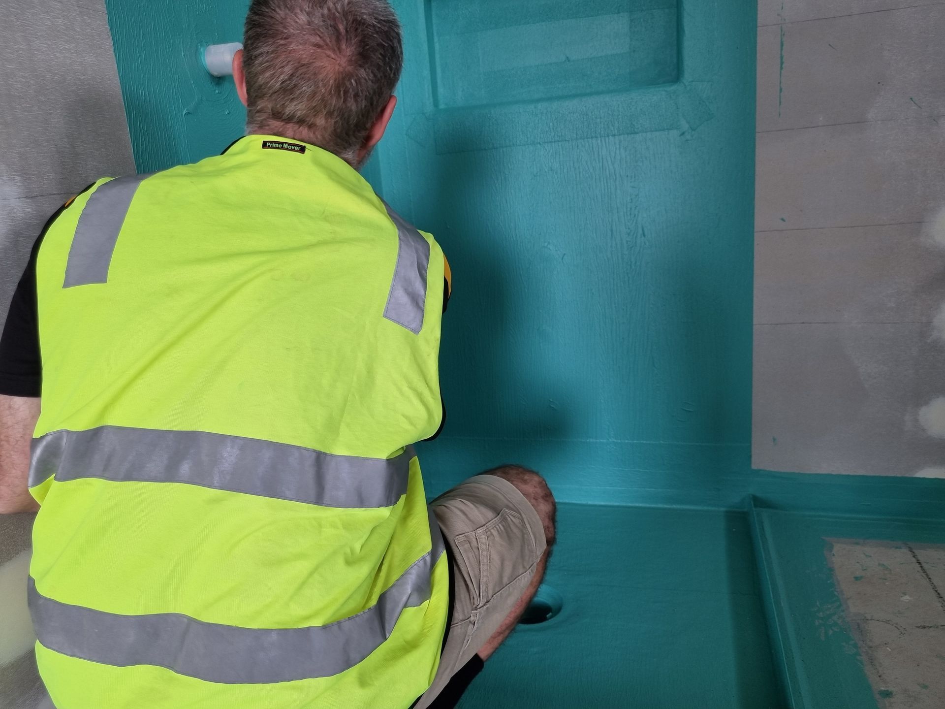 Person in a Safety Vest Applying Turquoise Sealant to a Shower Base — Acheson Building Certification in Nambucca Heads, NSW