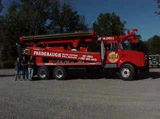 A red truck is parked on the side of a dirt road.