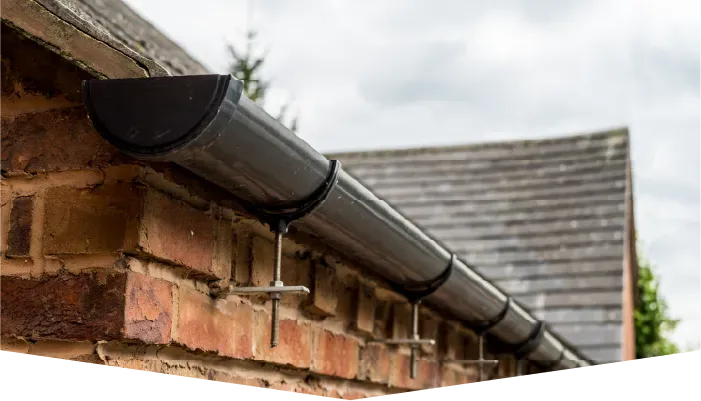A gutter is attached to the side of a brick building.