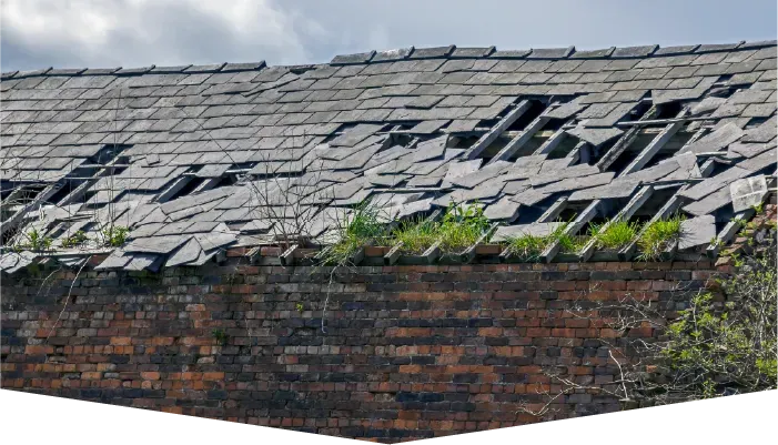 A brick wall with a roof that has been damaged by a storm.
