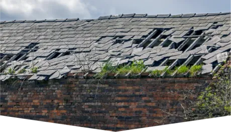 A brick wall with a roof that has been damaged by a storm.