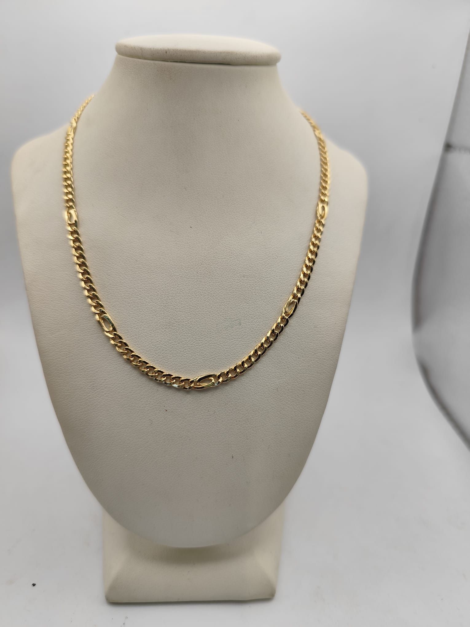 Collana a catena figaro in oro esposta su un busto di manichino beige.