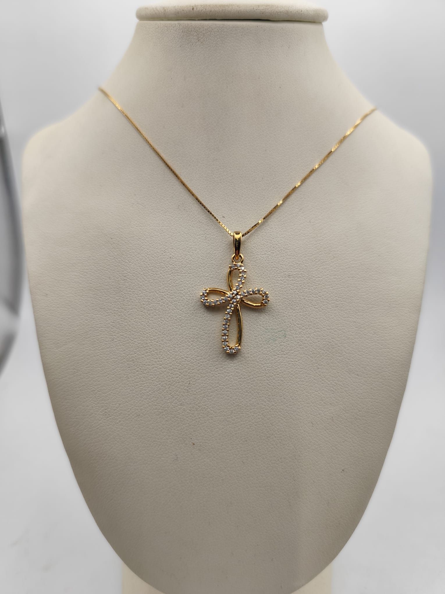 Ciondolo a forma di croce in oro con diamanti su manichino.