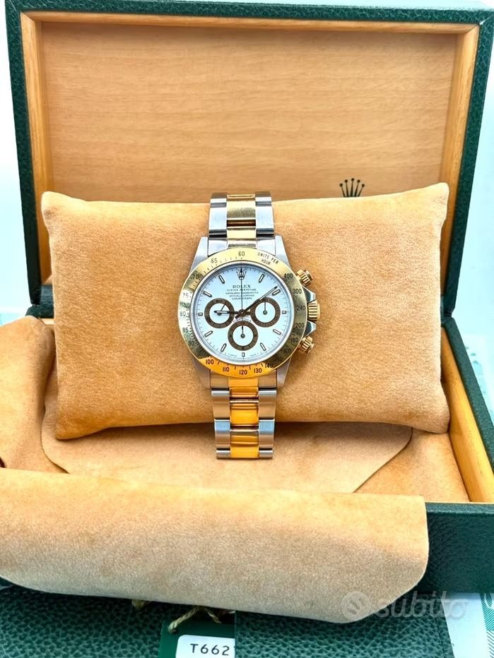Orologio Rolex Daytona in oro e argento su un cuscino di velluto marrone all'interno della sua scatola verde.