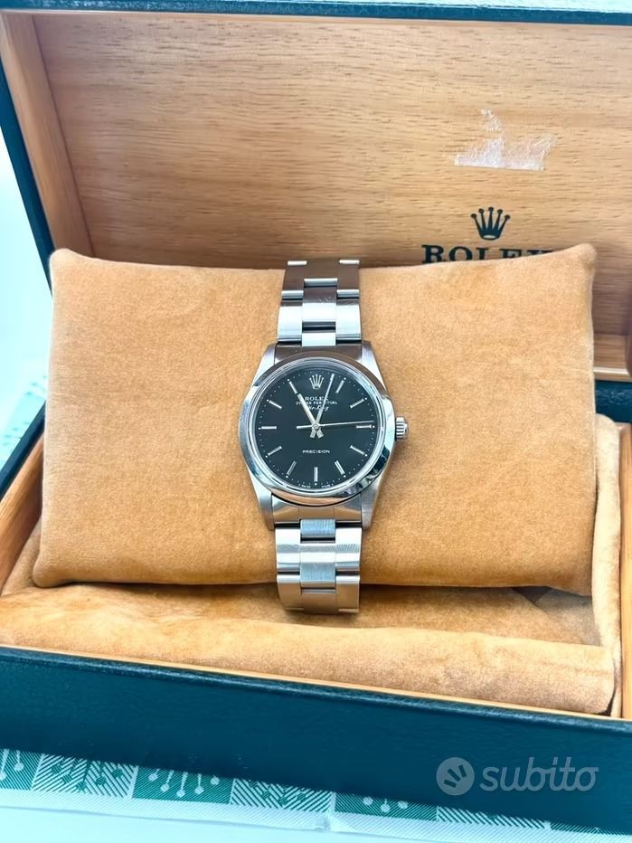 Orologio Rolex con quadrante nero e bracciale argentato in una scatola di legno aperta.